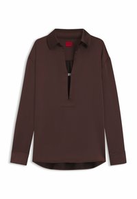 Camicia marrone a maniche lunghe con colletto a punta, mezza fila di bottoni e orlo leggermente curvo. Realizzata in tessuto liscio con una vestibilità rilassata.