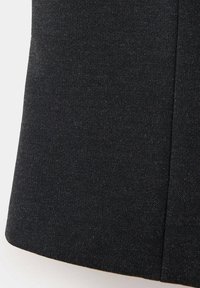 Gros plan sur un tissu gris foncé avec une texture fine en tricot et une couture verticale visible.