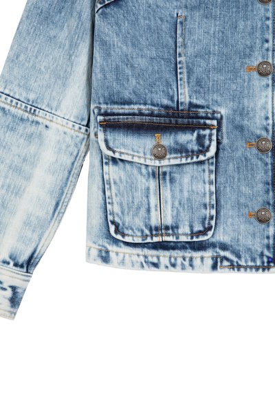 Veste en jean bleu clair avec une finition délavée, dotée d'une grande poche avant, d'une fermeture à boutons et de détails de couture orange contrastants.
