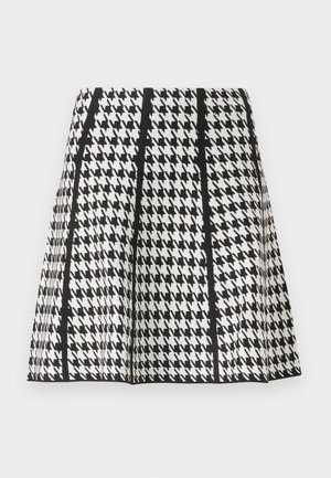 Jupe trapèze noire et blanche à motif pied-de-poule avec des rayures noires verticales sur un fond uni.