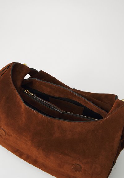 Geantă din suede maro cu o textură moale, un capac deschis și un buzunar cu fermoar în interior. Prezintă căptușeală neagră și accente de metal auriu.