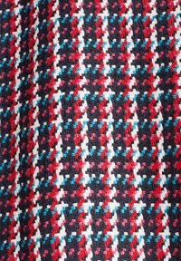 Nærbillede af vævet stof med et struktureret houndstooth-mønster i marineblå, rød, hvid og turkise farver.