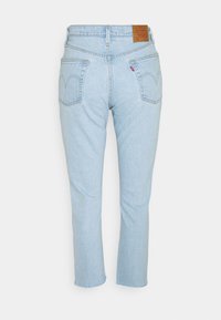 Jean en denim bleu clair avec une coupe droite, doté de deux poches arrière, de coutures discrètes et d'une étiquette en cuir marron sur la ceinture.