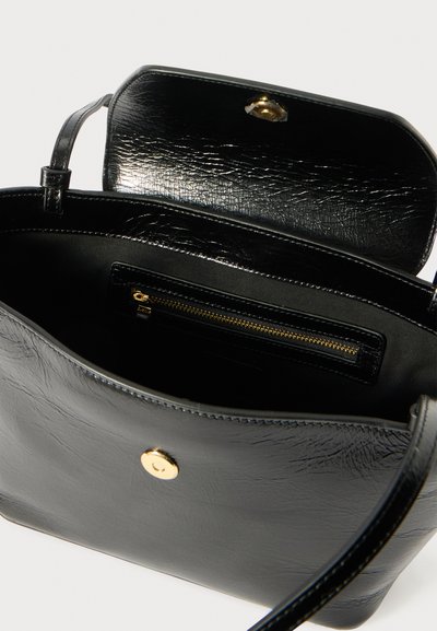 Melnas ādas rokassoma ar strukturētu apdari, aprīkota ar zelta spiedpogu un iekšējo rāvējslēdzēju. Iekļauts regulējams plecu siksniņa.