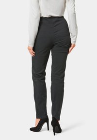 Zwarte, hoge taille broek in een slim fit, met een gladde textuur en subtiele stikdetails, gecombineerd met zwarte hoge hakken.