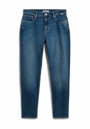 Vaqueros ajustados de mezclilla azul con bolsillos frontales, trabillas para cinturón, cierre de botones y un sutil desgaste en muslos y rodillas.
