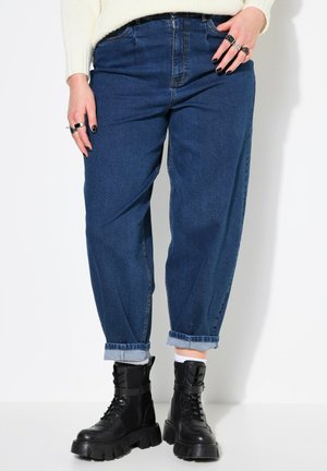 High-waisted, loose-fitting blue denim jeans with a cuffed hem, paired with chunky black lace-up boots. Includes side pockets and belt loops.