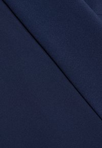 Tissu bleu marine présentant une texture lisse avec un accent nervuré. Le matériau semble léger et flexible, adapté à divers designs.