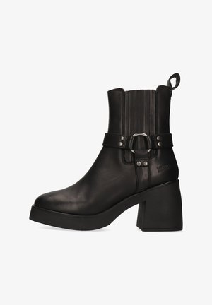 Bota de cuero negro para tobillo con puntera redondeada, tacón cuadrado, costuras laterales y una correa con un anillo metálico. Paneles texturizados en la caña.