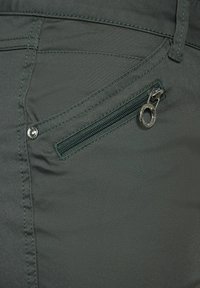 Pantalones verde oscuro con un bolsillo con cremallera que presenta un tirador plateado, textura suave y sutiles acentos de costura en la tela.