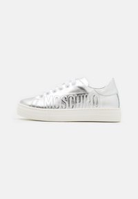 Silverfärgade lädersneakers med platta vita gummisålar, prydda med en upphöjd "MOSCHINO"-logotyp längs sidan och runda vita snören.