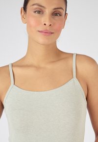 Canottiera grigia chiara con spalline sottili. Morbido tessuto a costine e scollatura arrotondata. Nessun motivo o decorazione evidente visibile.