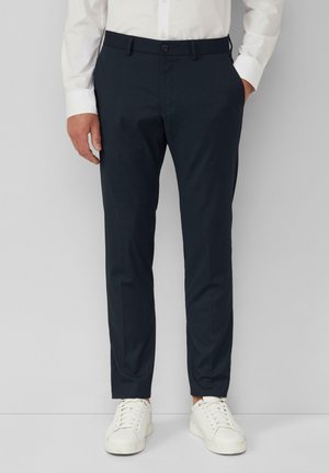 Navy blue tailored pants with a straight fit, made from a smooth fabric, featuring a button closure and side pockets, paired with white sneakers.