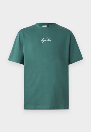 Roheline puuvillane T-särk, mis on varrukateta ja ringkraega. Ees on valge kalligraafiline tekst "high tea". Lihtne disain, ilma mustriteta.