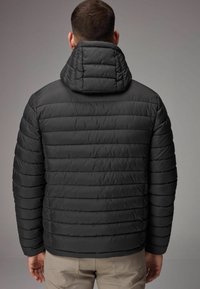 Jachetă puffer neagră cu design cu panouri cusute și guler înalt, având o textură netedă și material izolat.