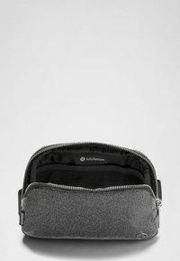 Bolsa de tela gris con cierre de cremallera, con interior negro y un bolsillo de malla. Logotipo visible en el interior. Textura suave y forma compacta.