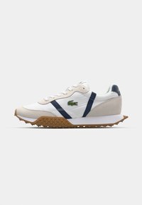 Witte sneaker met marineblauwe accenten, rubberen buitenzool en een getextureerde tan tussenzool. Beschikt over een vetersluiting en een groene krokodillenlogo aan de zijkant.