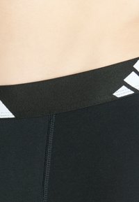 Shorts de sport noirs avec une large ceinture élastique ornée d'accents géométriques blancs et de coutures à plat pour plus de confort.