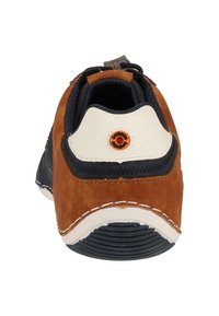 Chaussure en suede marron avec des accents en textile bleu marine, bout arrondi, talon blanc et détail circulaire orange à l'arrière. Semelle en caoutchouc avec des rainures horizontales.