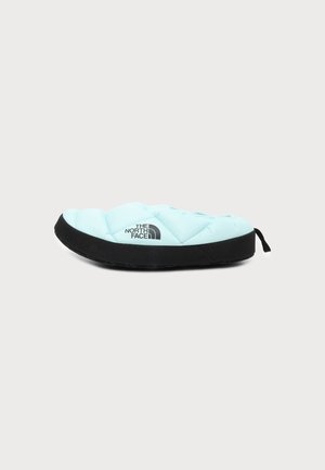 Chausson bleu clair matelassé à enfiler avec semelle noire et languette, avec le logo The North Face sur le côté.