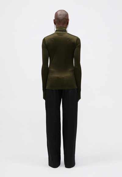 Top mulat, cu mâneci lungi, ajustat, cu guler înalt; asortat cu pantaloni negri, largi; textură de stofă netedă; design minimalist.
