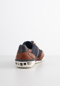 Brown leather and navy mesh sneaker with a textured surface, featuring a white rubber sole embossed with "bugatti" on the heel.