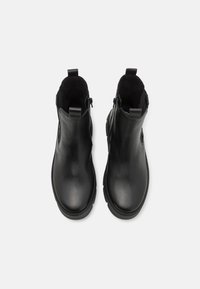 Paire de bottines noires en cuir avec fermetures éclair latérales et languettes, vues de dessus sur fond blanc.