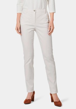 Witte, slim-fit broek met een gladde textuur en voorzakken, gecombineerd met bruin hoge hakken. Kenmerkt zich door een enkele knoopsluiting.