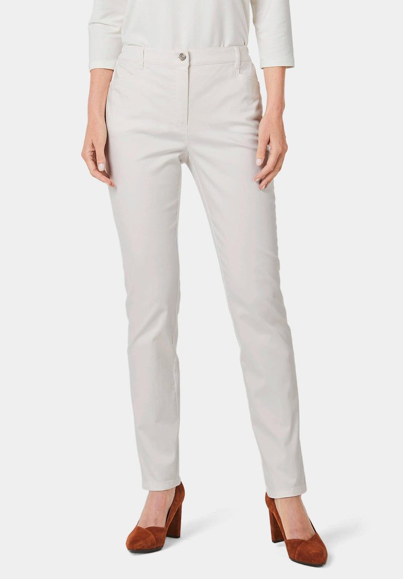 Witte, slim-fit broek met een gladde textuur en voorzakken, gecombineerd met bruin hoge hakken. Kenmerkt zich door een enkele knoopsluiting.