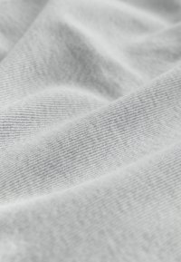 Világosszürke szövet, finom, szőtt textúrával. A felszíne simának tűnik, finom redőkkel, amelyek diszkrét, egységes mintát mutatnak.