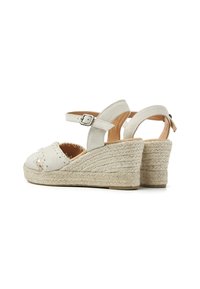 White leather wedge sandals with braided jute platform, featuring a buckle strap and stitched detail on the toe area.
