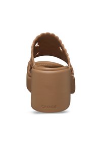 Sandales Crocs brunes avec un talon épais, design festonné sur la sangle et semelle texturée. Marque visible sur le côté.
