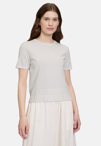 Krótki rękaw w jasnoszarym kolorze z mieszanki bawełny, z okrągłym dekoltem i prostym wykończeniem, w zestawieniu z falującą kremową spódnicą.