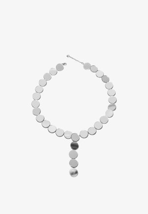 Srebrna ogrlica s okruglim diskovima povezanim zajedno, s duljim visećim dijelom u sredini. Glatka, sjajna površina s ujednačenim dizajnom.