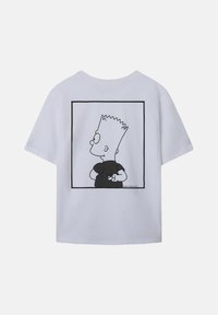 Witte katoenen t-shirt met een zwart-wit grafiek van een cartoonfiguur tegen een vierkant kader op de achterkant. Korte mouwen, ronde hals.