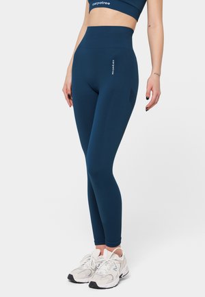 High-waisted navy blue leggings made from elastic material with a ribbed texture and a side pocket. Paired with light-colored sneakers.