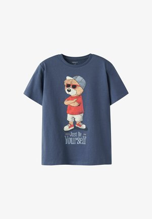 Tumši zila T-krekls ar grafiku, kurā attēlots lācis sarkanās saulesbrillēs, sarkanā krekliņā, baltās šortos, sporta apavos un cepurē, teksta "Vienkārši esi pats."