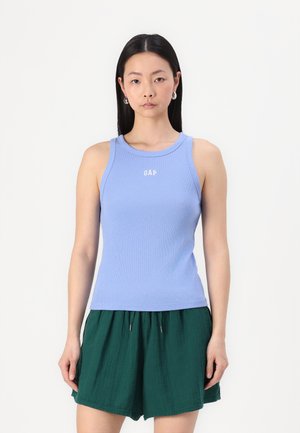 Light blue ribbed tank top with a round neckline and GAP logo in white; paired with green pleated shorts. Smooth texture, fitted design.