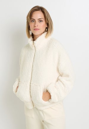 Crème kleurige fleecejas met hoge kraag, ritssluiting en oversized zakken. De gestructureerde stof en de relaxte fit bieden warmte.