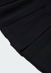 Tessuto nero a pieghe con dettagli di cucitura visibili lungo l'orlo, che mostrano texture e strati piegati.