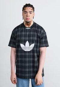 Juodas languotas marškinėliai su baltu Adidas logotipu priekyje, suapvalintu iškirpimu ir trumpomis rankovėmis, pagaminti iš lengvos medžiagos.