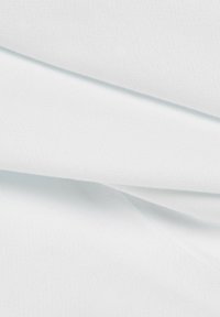Tissu blanc plié avec une texture lisse et une apparence douce montré en gros plan.