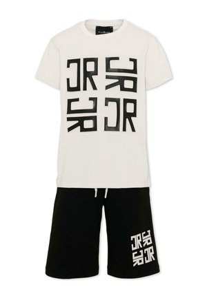 T-shirt bianca a manica corta con stampa del testo geometrico nero abbinata a pantaloncini neri con testo bianco abbinato sulla gamba sinistra.