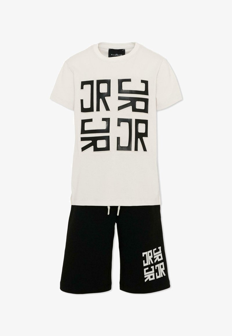 T-shirt blanc à manches courtes avec impression de texte géométrique noire, associé à un short noir avec un texte blanc assorti sur la jambe gauche.