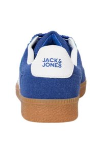 Blue suede sneaker with white heel tab featuring "JACK & JONES" logo. Rubber sole with textured finish, lace-up design, and padded collar.