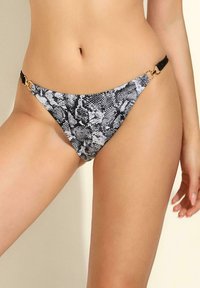 Czarny i biały kostium kąpielowy w wężowy wzór, z tr ójkątnym kształtem, ozdobiony złotym metalowym akcentem i regulowanymi czarnymi staniczkami.