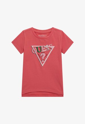 T-shirt in cotone corallo con maniche corte, caratterizzato da un design del logo triangolare in bianco, verde e argento con testo "GUESS" e dettagli in metallo.