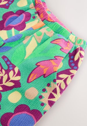 Tessuto colorato con grandi motivi floreali e fogliari nelle tonalità di verde, viola, rosa e arancione, con una superficie strutturata.