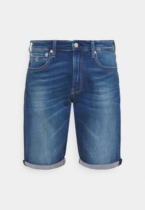 Short en denim bleu avec revers roulés, bouton et fermeture éclair à l'avant, passants pour ceinture, et poches avant avec petit logo sur la poche droite.