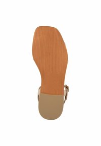 Sandalo con tacco beige caratterizzato da una suola in brown testurizzata, cinturino alla caviglia regolabile e un design a punta arrotondata con una finitura liscia.